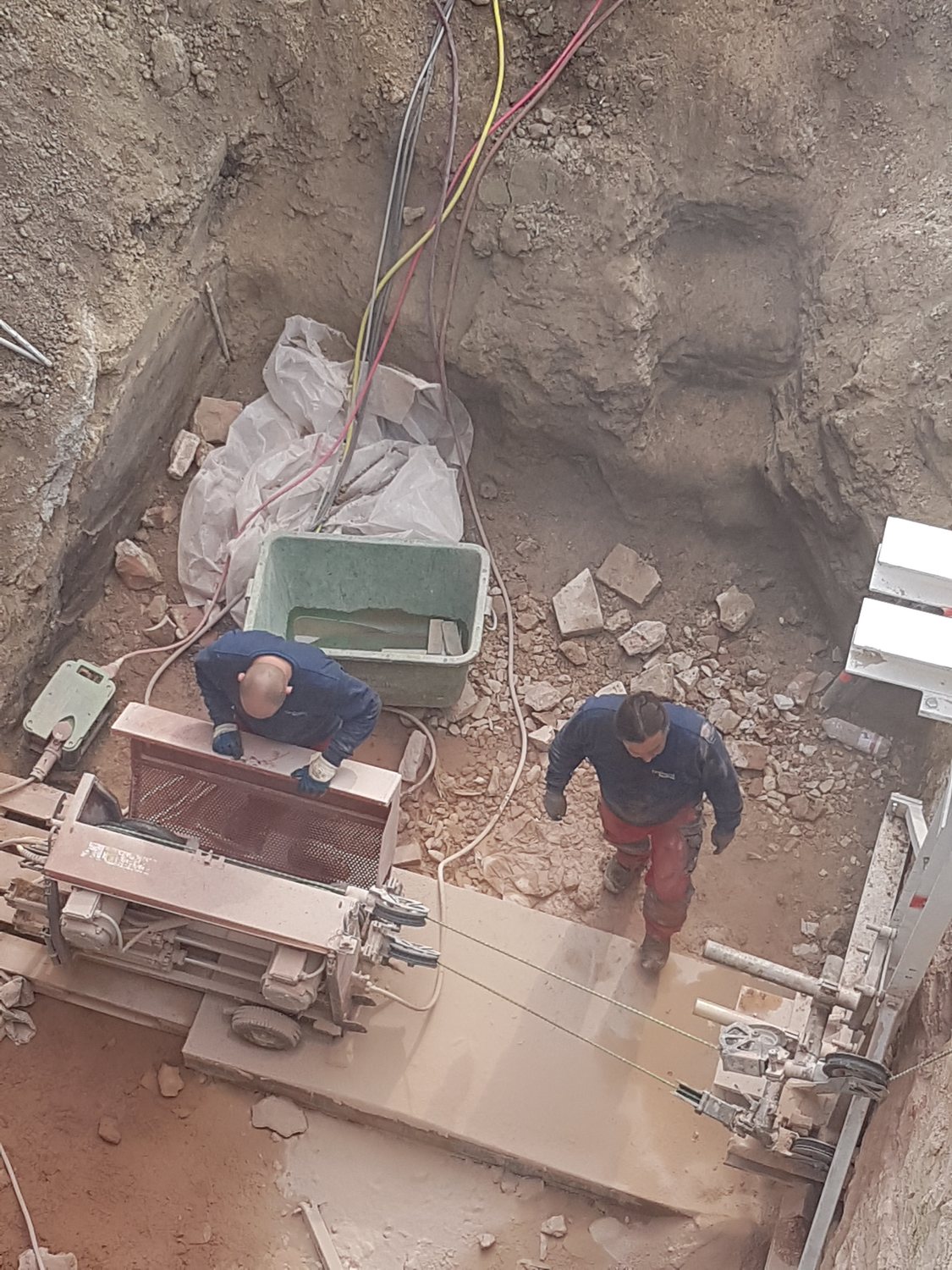 Zwei Monteure trennen mit der Seilsäge eine Scheibe aus der Stadtmauer
