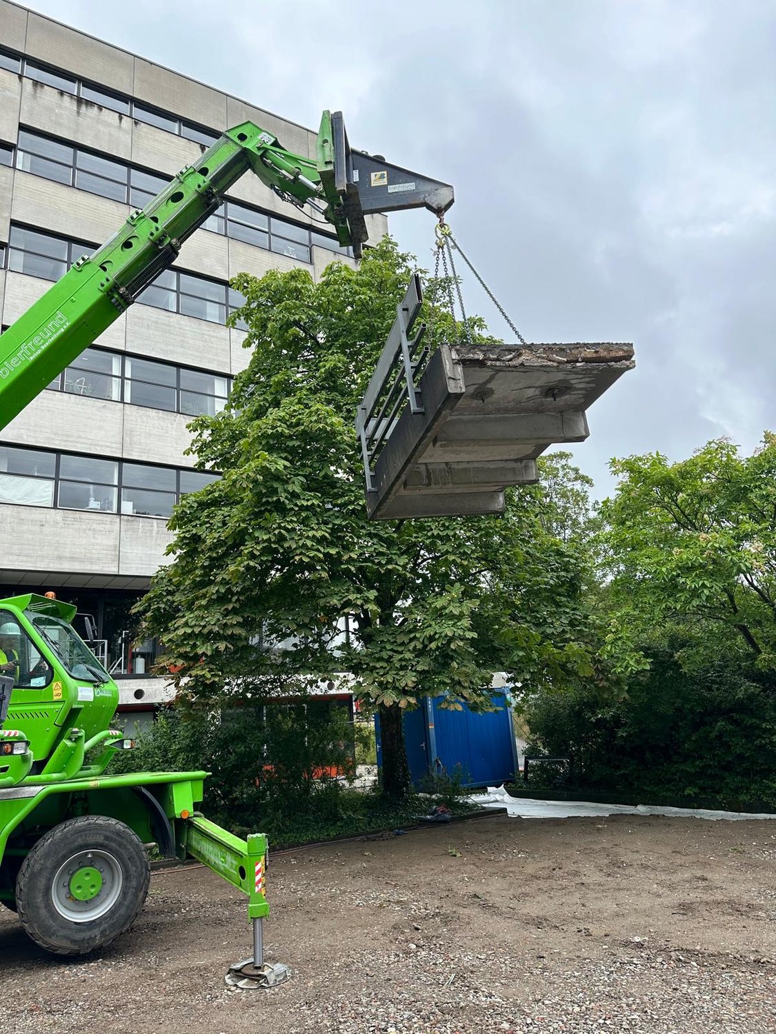 Grüner bierfreund-Teleskoplader hebt ein herausgetrenntes Betonbauteil