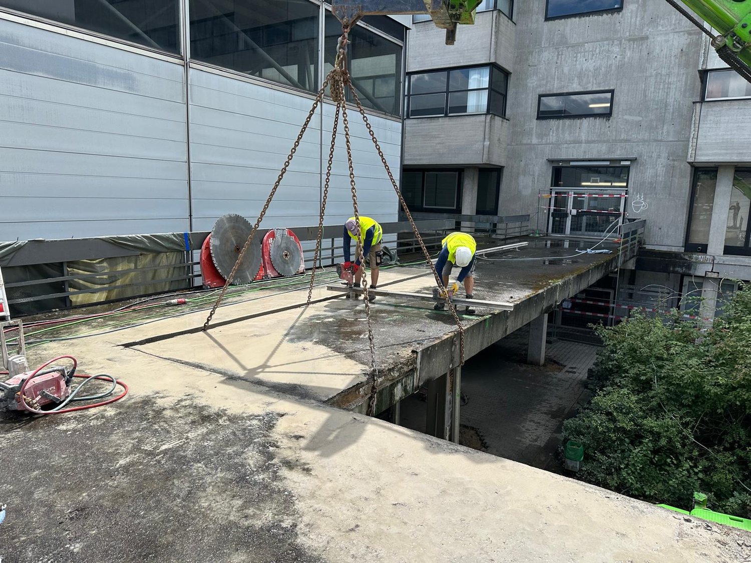 Zwei Monteure trennen mit der Säge ein Deckenbauteil zum Ausheben